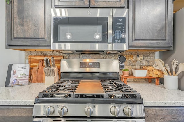 kitchen featuring light stone counters, backsplash, and appliances with stainless steel finishes