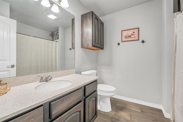 bathroom with toilet, vanity, and hardwood / wood-style flooring