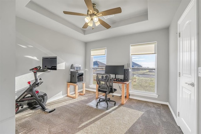 carpeted home office featuring ceiling fan and a raised ceiling