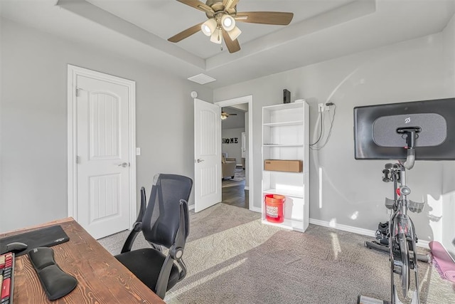 office featuring ceiling fan, light colored carpet, and a tray ceiling