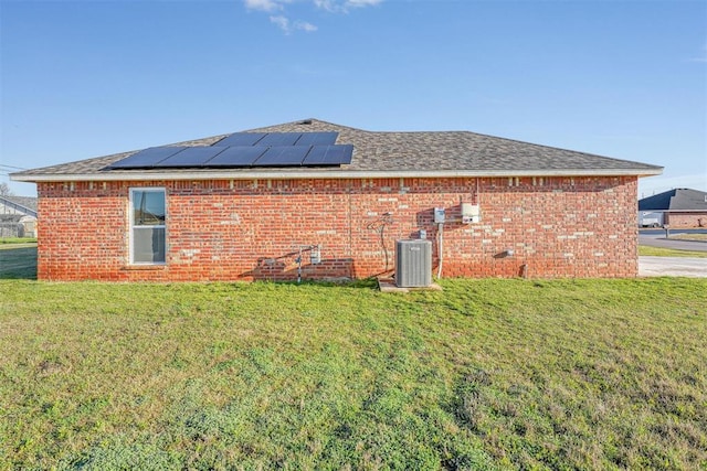 back of house featuring a yard and solar panels