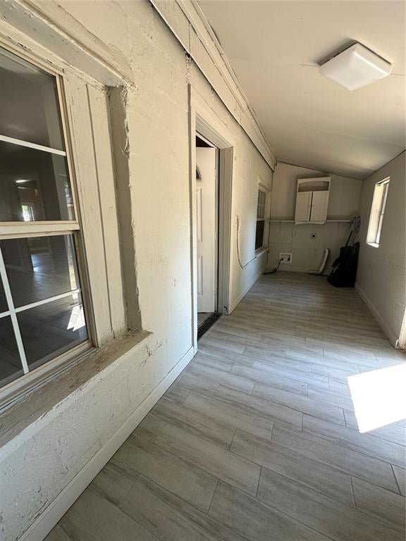 hall with light hardwood / wood-style floors and vaulted ceiling