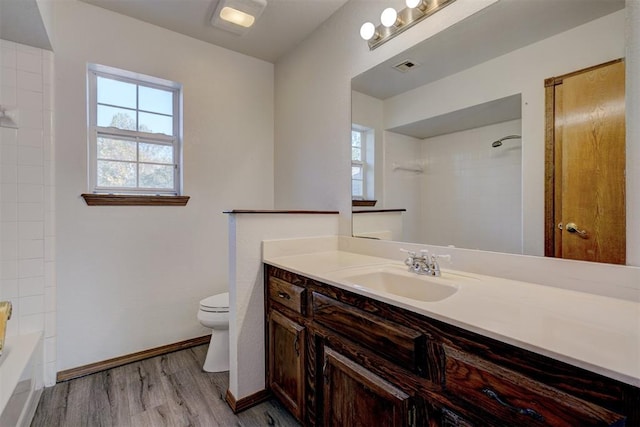 full bathroom featuring tiled shower / bath, hardwood / wood-style floors, vanity, and toilet