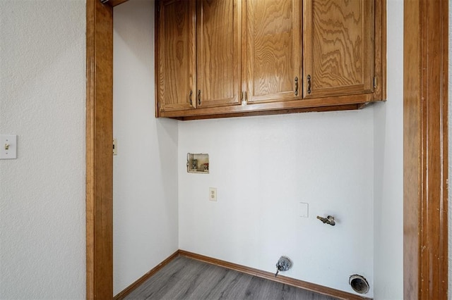 washroom with hookup for a washing machine, cabinets, and light hardwood / wood-style flooring