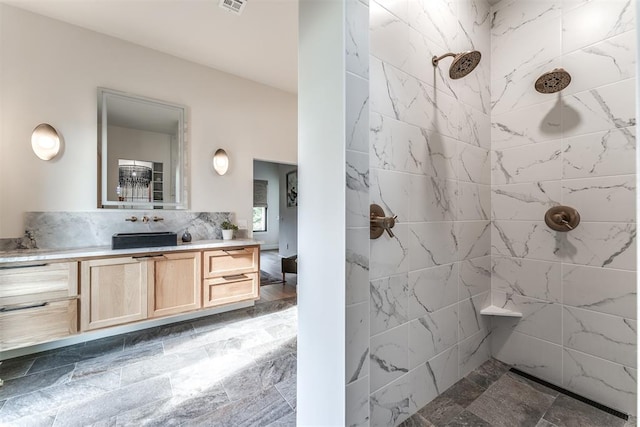 bathroom with a tile shower and vanity