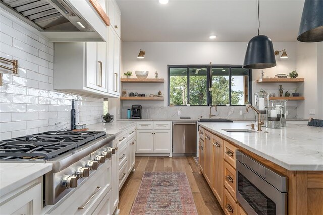 kitchen with decorative backsplash, appliances with stainless steel finishes, light stone counters, custom range hood, and white cabinets