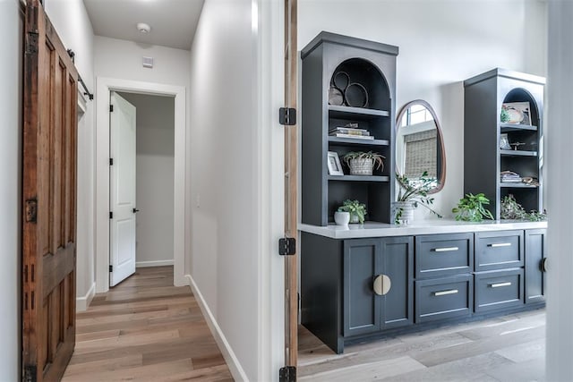 hallway with a barn door, light hardwood / wood-style floors, and built in features