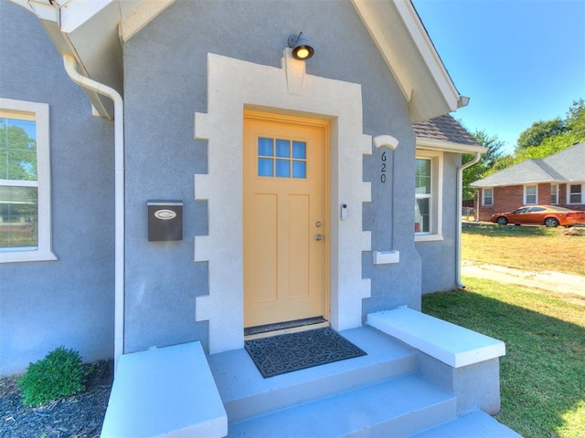 view of exterior entry with a lawn