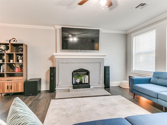 living room featuring ceiling fan, dark hardwood / wood-style flooring, ornamental molding, and a brick fireplace