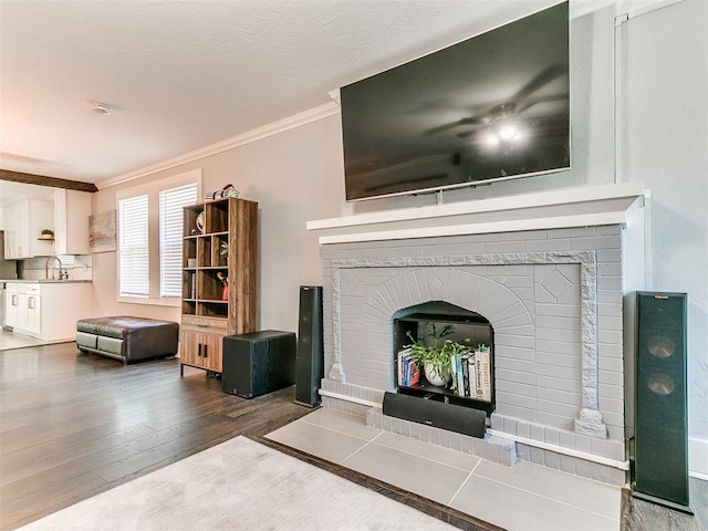 unfurnished living room featuring crown molding, a fireplace, dark wood-type flooring, and sink