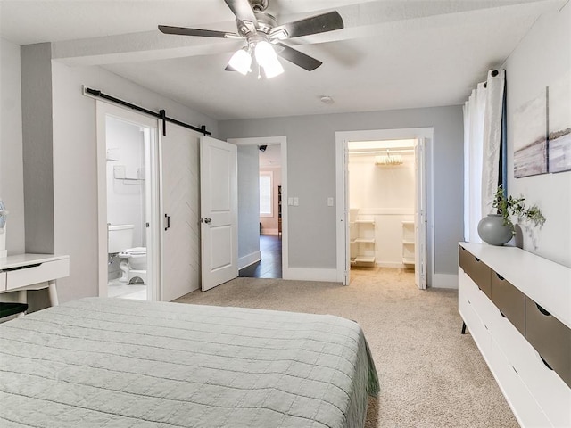 bedroom featuring ceiling fan, a barn door, light colored carpet, and ensuite bath