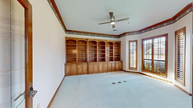 spare room with ceiling fan, crown molding, and light carpet