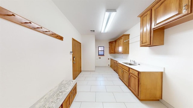 kitchen featuring light stone counters, sink, and light tile patterned floors