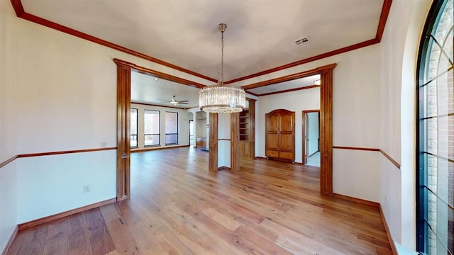 unfurnished dining area featuring ceiling fan with notable chandelier, light wood-type flooring, and crown molding