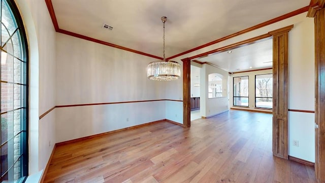 unfurnished dining area with crown molding, an inviting chandelier, and light wood-type flooring