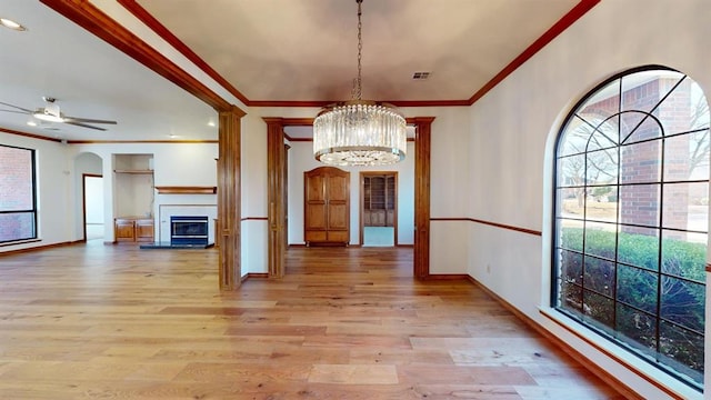 unfurnished dining area featuring crown molding, light hardwood / wood-style flooring, and ceiling fan with notable chandelier