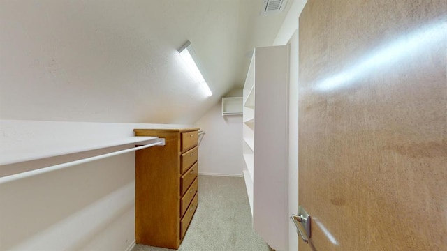 spacious closet featuring light colored carpet and vaulted ceiling