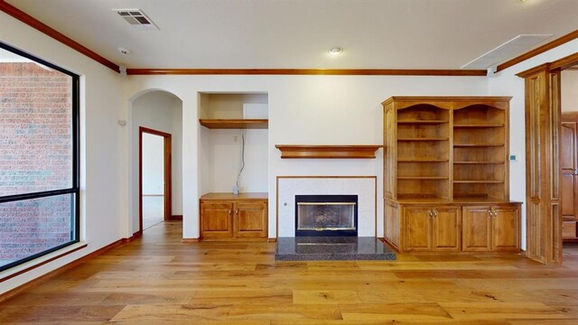 unfurnished living room featuring light hardwood / wood-style floors, crown molding, and a fireplace