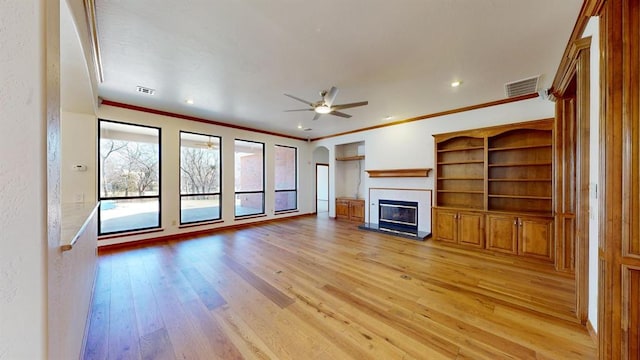 unfurnished living room featuring light hardwood / wood-style floors, ceiling fan, and ornamental molding