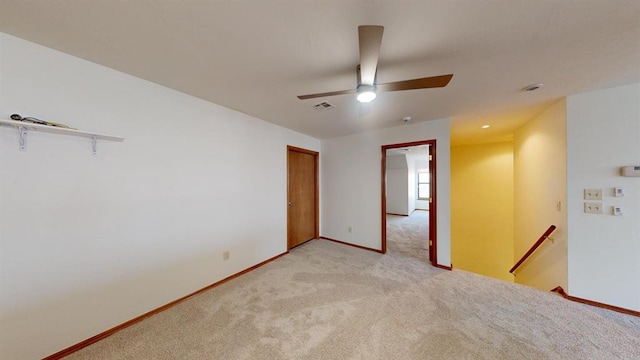 empty room featuring ceiling fan and light carpet