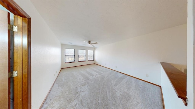 empty room featuring ceiling fan and light carpet