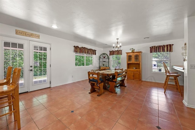 dining area with tile patterned floors, an inviting chandelier, a wealth of natural light, and french doors