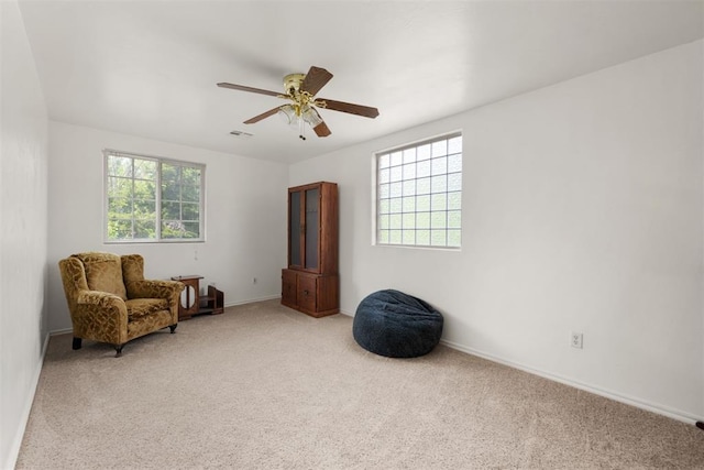 living area with light carpet, plenty of natural light, and ceiling fan