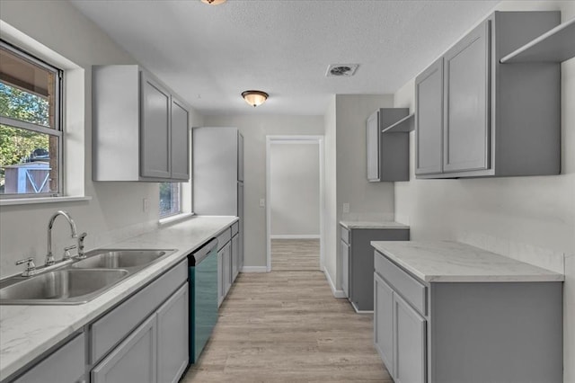 kitchen featuring gray cabinetry, dishwasher, sink, a textured ceiling, and light wood-type flooring