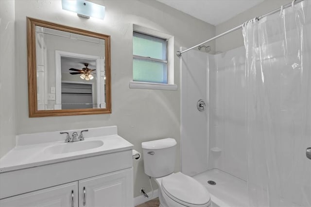 bathroom with walk in shower, ceiling fan, vanity, and toilet