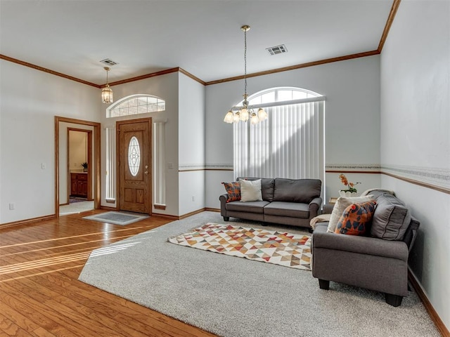 entrance foyer with visible vents, wood finished floors, crown molding, baseboards, and a chandelier