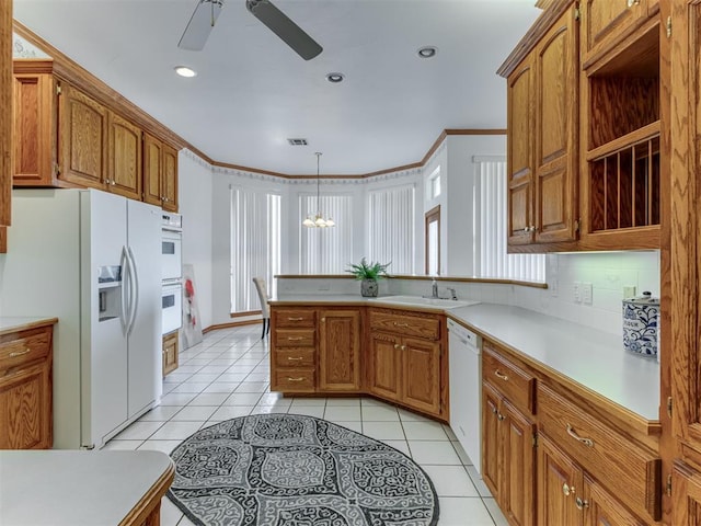 kitchen with a sink, white appliances, light countertops, and light tile patterned floors