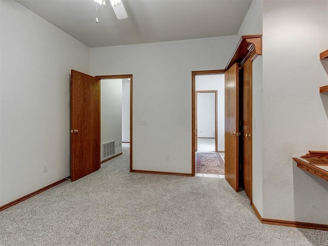 carpeted empty room featuring visible vents, ceiling fan, and baseboards