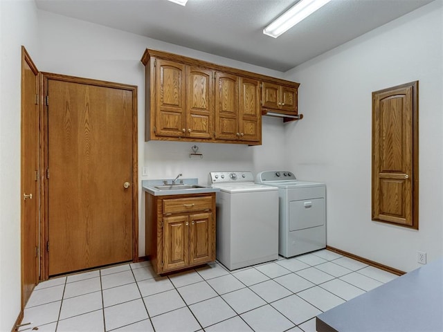 laundry room featuring light tile patterned flooring, cabinet space, washer and dryer, and a sink