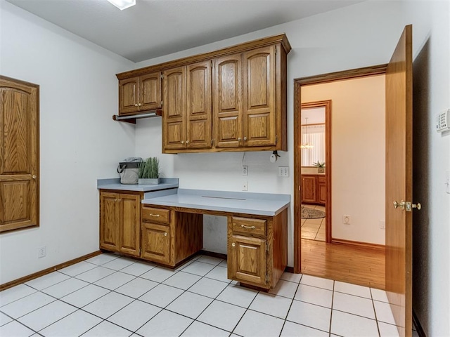 kitchen with light countertops, light tile patterned flooring, baseboards, and brown cabinets