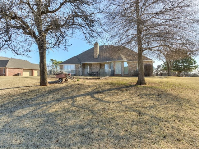 view of front facade with a front yard, fence, brick siding, and a chimney