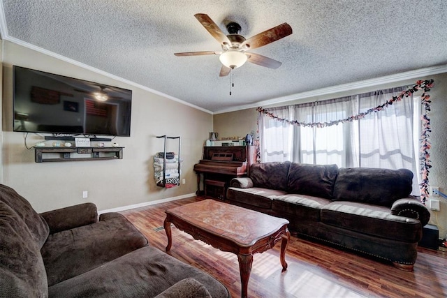 living room with a ceiling fan, wood finished floors, baseboards, ornamental molding, and a textured ceiling