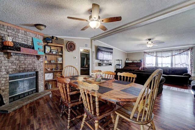 dining room featuring vaulted ceiling, ornamental molding, a fireplace, wood finished floors, and a textured ceiling