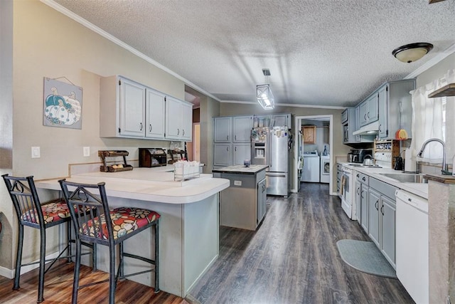 kitchen with white appliances, a peninsula, separate washer and dryer, a sink, and crown molding