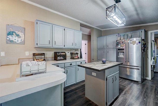 kitchen with crown molding, dark wood finished floors, light countertops, stainless steel fridge, and a textured ceiling