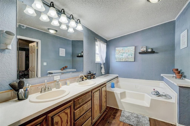 full bath with wood finished floors, a textured ceiling, a textured wall, and a sink