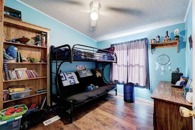 bedroom featuring a ceiling fan, wood finished floors, lofted ceiling, ornamental molding, and a textured ceiling