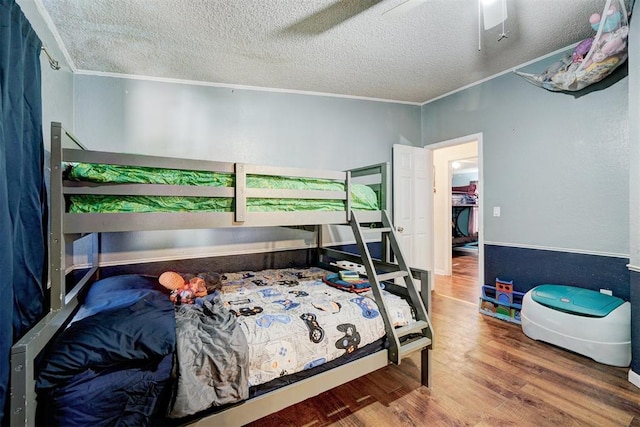 bedroom featuring a textured ceiling, wood finished floors, and crown molding