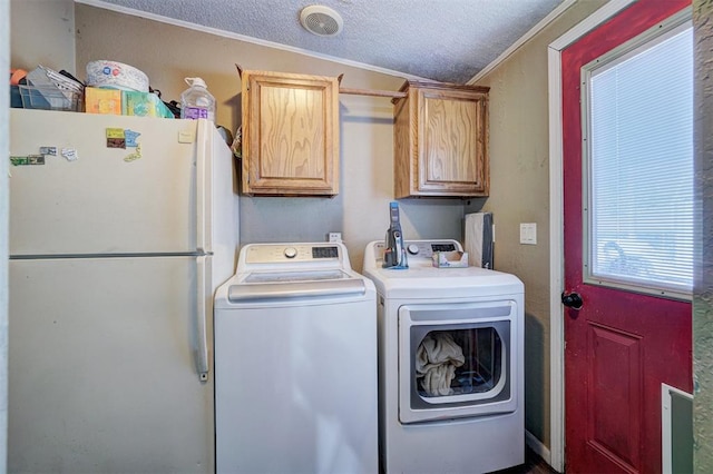 washroom featuring visible vents, crown molding, washing machine and dryer, cabinet space, and a textured ceiling