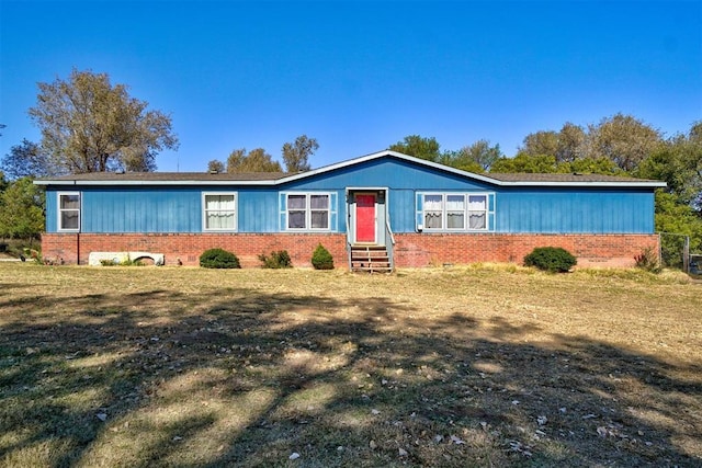 view of front of house with entry steps, a front yard, and brick siding