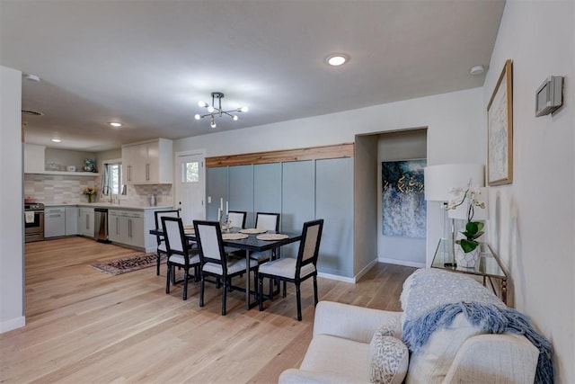 dining area with a chandelier, sink, and light hardwood / wood-style floors