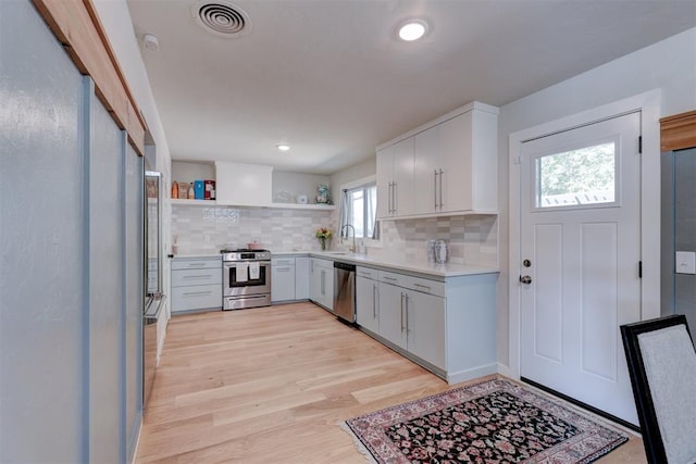 kitchen featuring sink, stainless steel appliances, tasteful backsplash, light hardwood / wood-style floors, and white cabinets