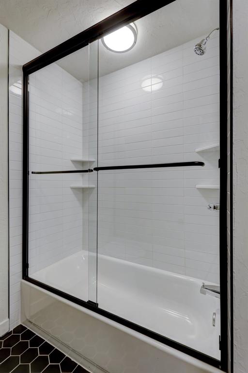 bathroom with shower / bath combination with glass door and tile patterned flooring