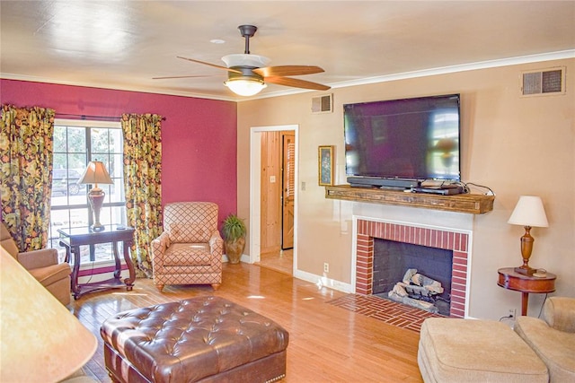 living room featuring a brick fireplace, ceiling fan, ornamental molding, and hardwood / wood-style flooring