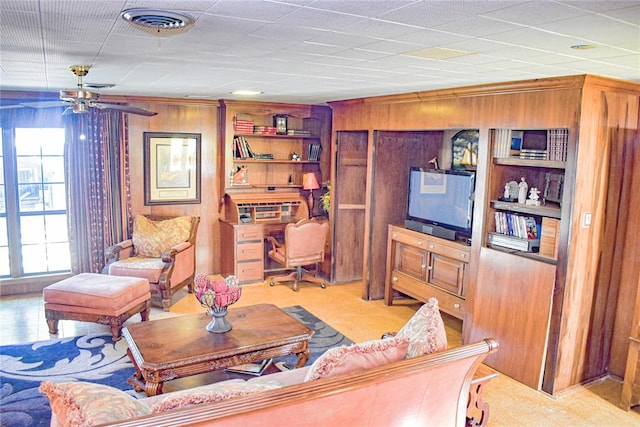 living room featuring built in features, ceiling fan, and wood walls