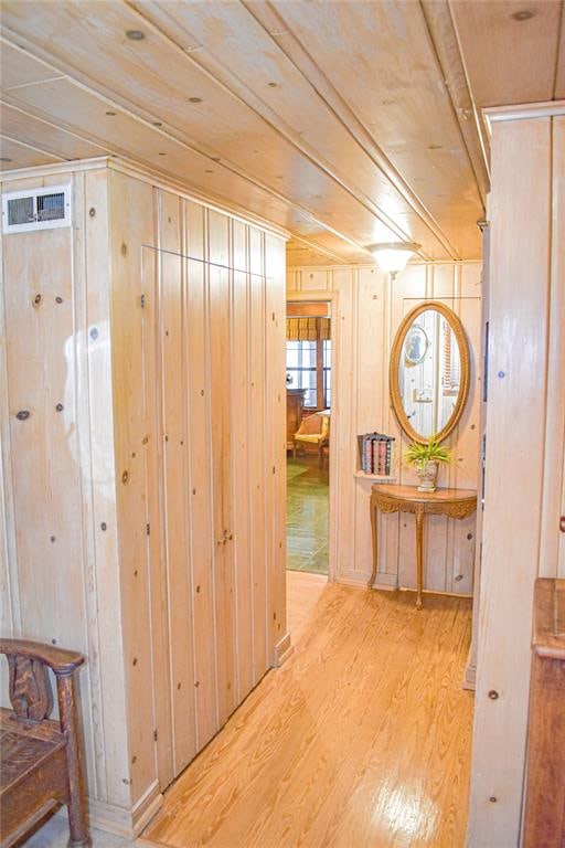 hall with wood walls and light wood-type flooring